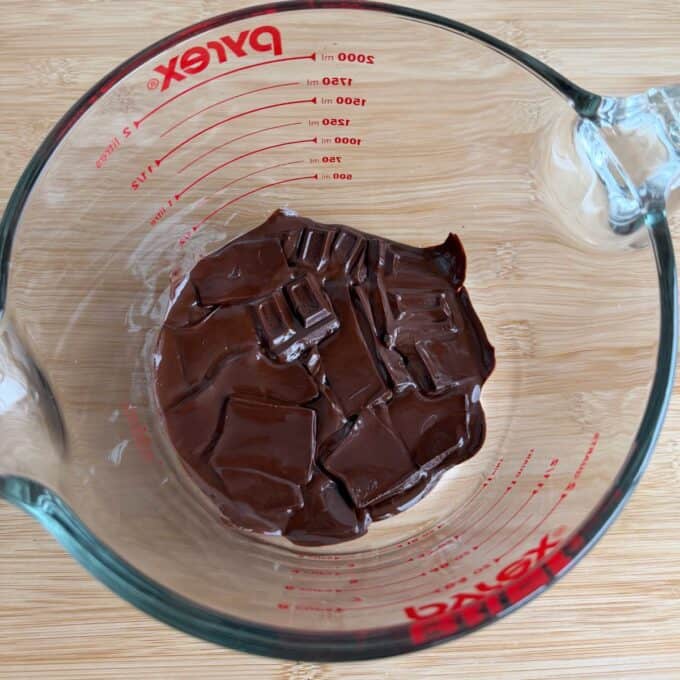 Snickers Peanut Butter Bites Pieces of chocolate melting in a glass Pyrex measuring cup.